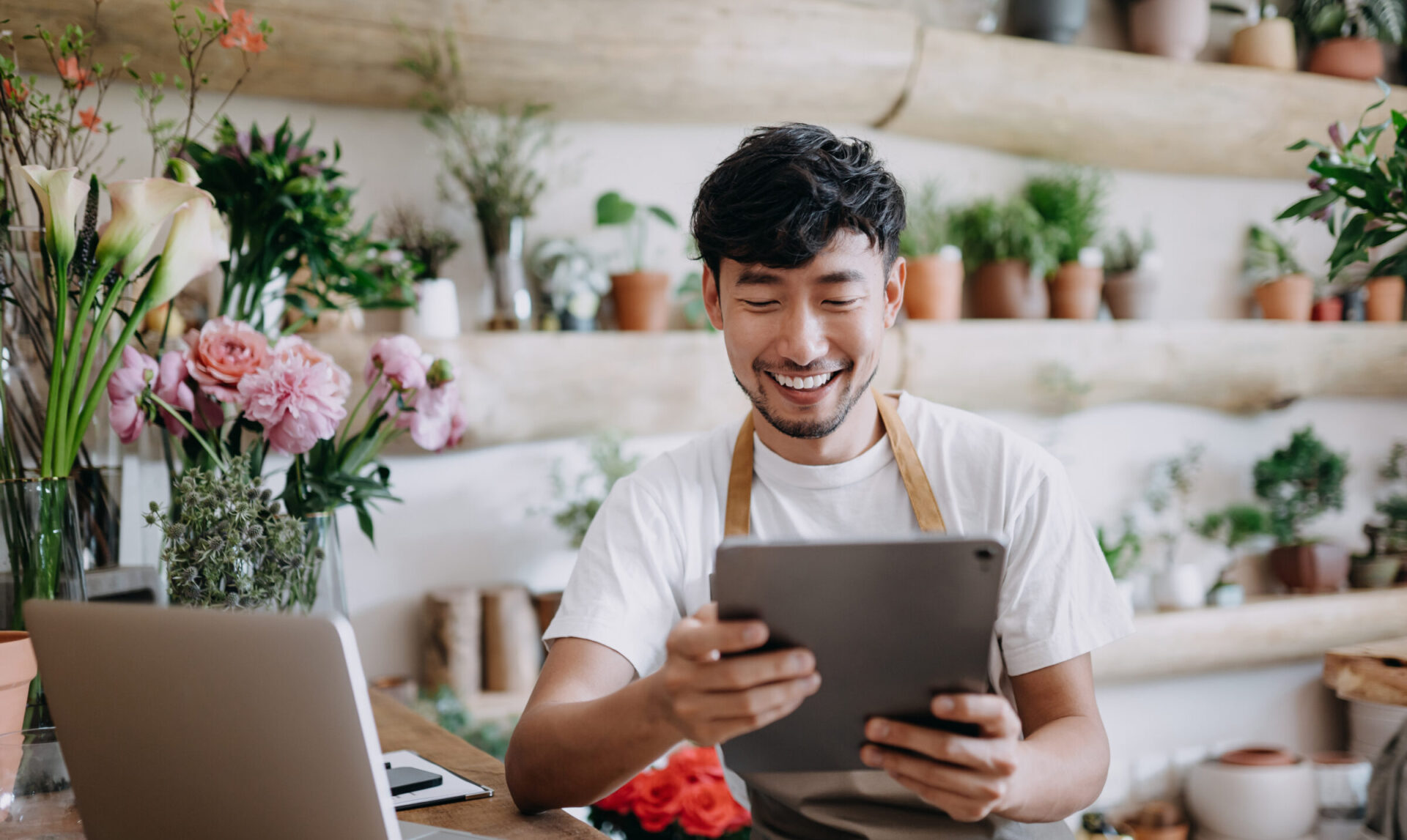 Bloemist aan het werk op zijn laptop en tablet in de plantenwinkel