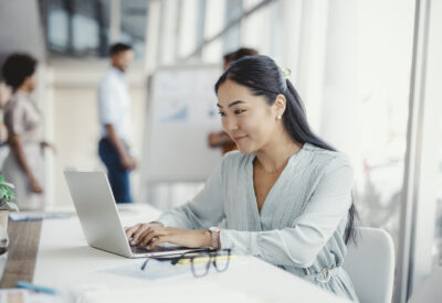 Vrouw aan het werk achter haar laptop met collega's op de achtergrond