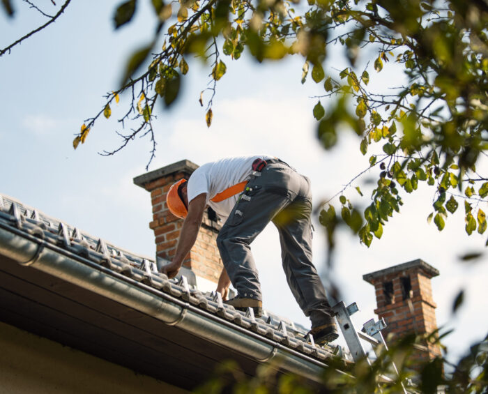 Man in veiligheidskleding die aan het dak werkt