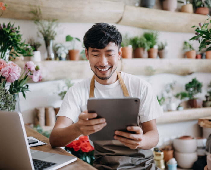 Bloemist aan het werk op zijn laptop en tablet in de plantenwinkel