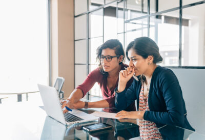 Twee vrouwen die samen naar een laptop kijken