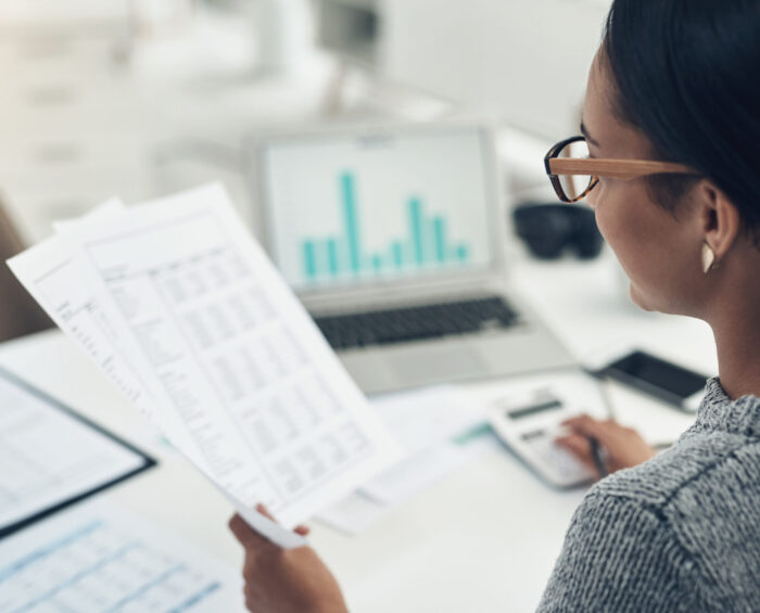 Vrouw aan het werk bezig met haar laptop en documenten met data